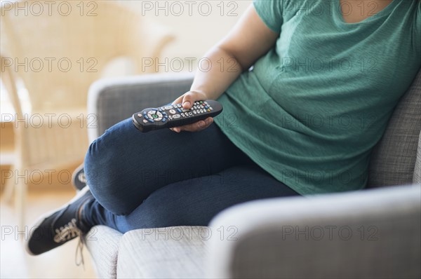 Woman sitting on sofa with remote control.