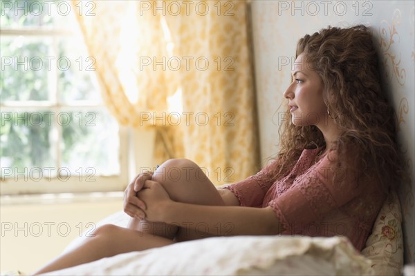 Portrait of woman sitting on bed.