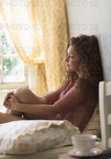 Portrait of woman sitting on bed.