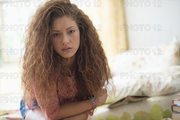 Portrait of woman sitting on bed.