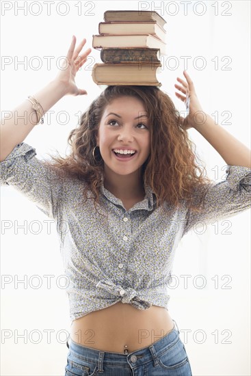 Portrait of woman with books on top of head.