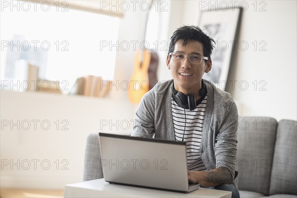 Portrait of man with headphones in front of laptop.