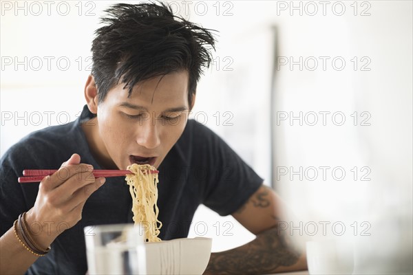 Man eating noodles with chopsticks.