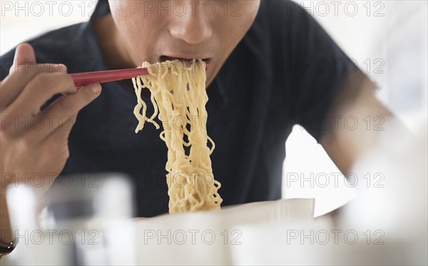 Man eating noodles with chopsticks.