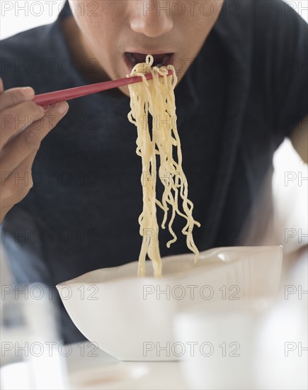 Man eating noodles with chopsticks.