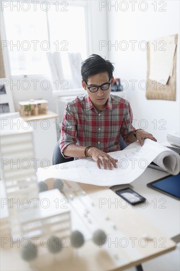 Architect looking at blueprints in office.
