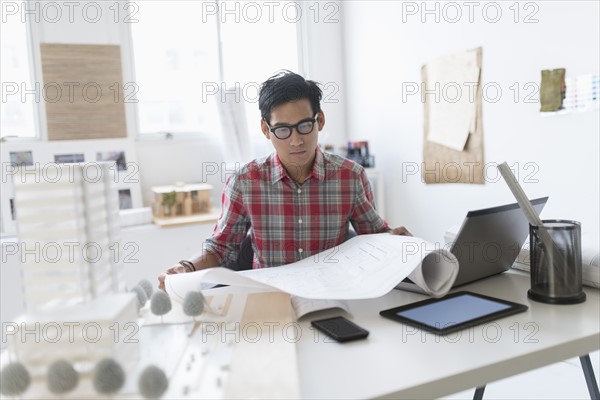 Architect looking at blueprints in office.
