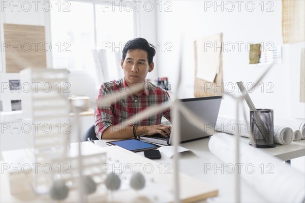 Wind turbine models on desk in front of architect.