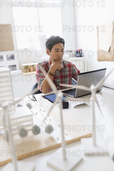 Wind turbine models on desk in front of architect.