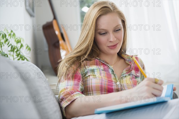 Portrait of young woman writing journal on sofa