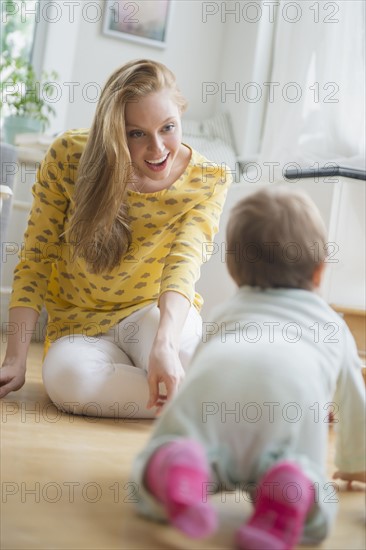 Mother looking at baby daughter (6-11 months) crawling