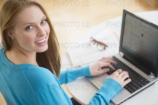 Smiling young woman using laptop