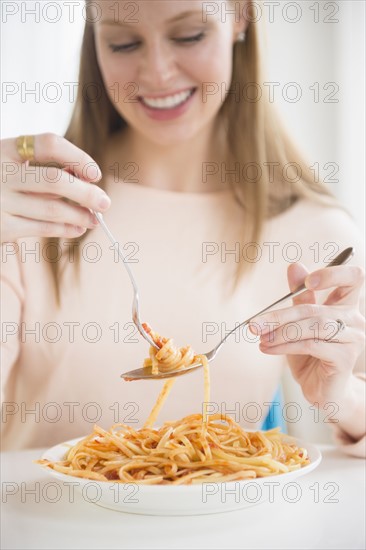 Young woman eating fettuccini