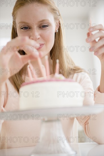 Woman putting candles on birthday cake