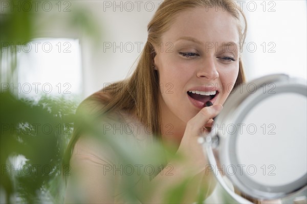 Young woman applying lipstick