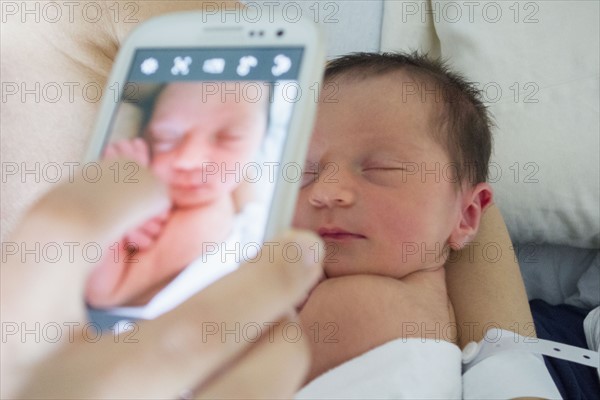 Mother photographing newborn daughter