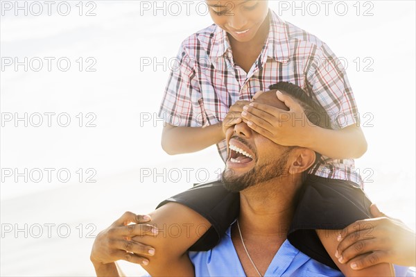 Father and son (10-11) having fun on beach