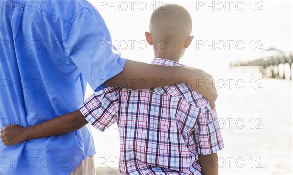 Father and son (10-11) embracing on beach