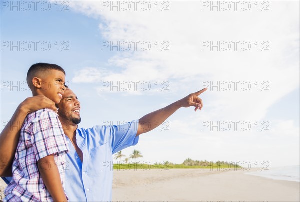 Father and son (10-11) embracing on beach