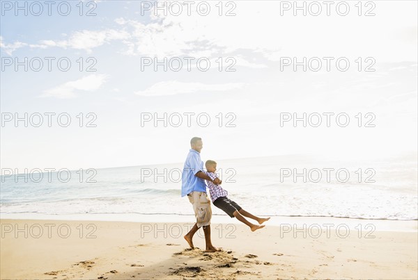 Father and son (10-11) having fun on beach