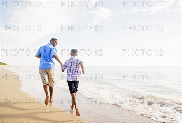 Father and son (10-11) running on beach