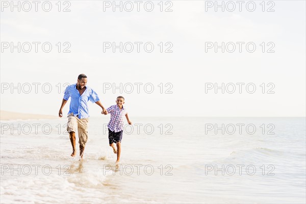 Father and son (10-11) running on beach