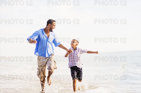 Father and son (10-11) running on beach