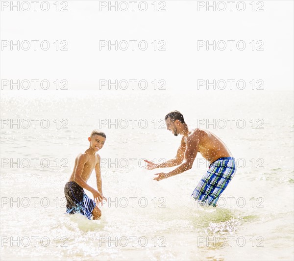 Father and son (10-11) having fun on beach