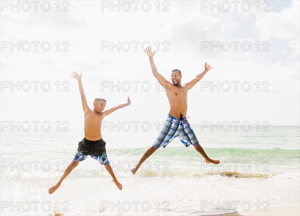 Father and son (10-11) having fun on beach
