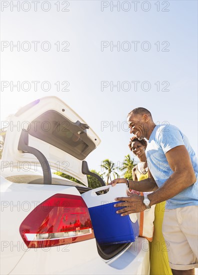 Mature couple loading car trunk