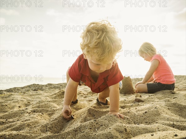 Girl (4-5) and boy (2-3) playing on beach