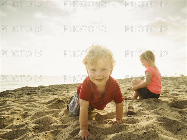 Girl (4-5) and boy (2-3) playing on beach