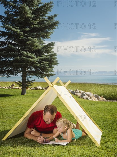 Father and daughter (2-3) playing in tent