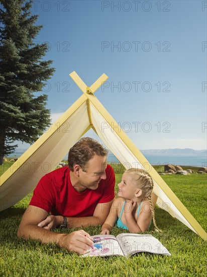 Father and daughter (2-3) playing in tent