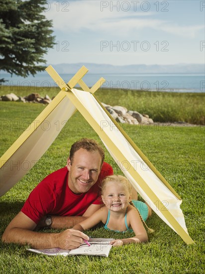 Father and daughter (2-3) playing in tent