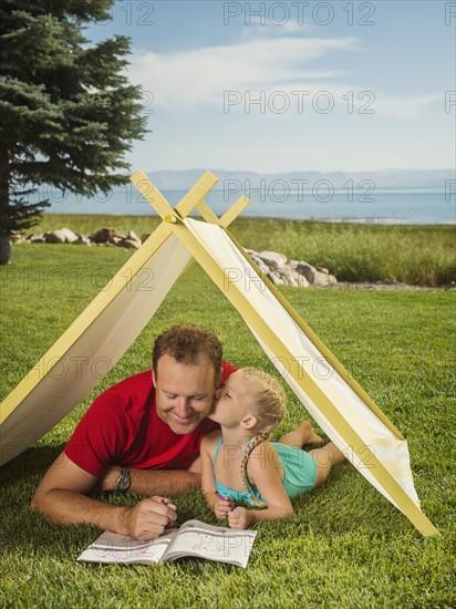 Father and daughter (2-3) playing in tent