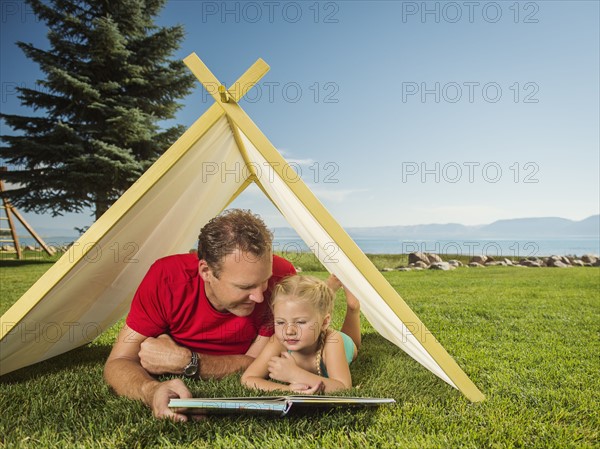 Father and daughter (2-3) playing in tent