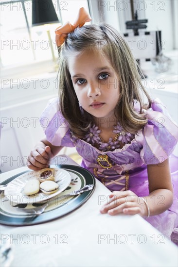 Girl (4-5) eating cookies at dining table