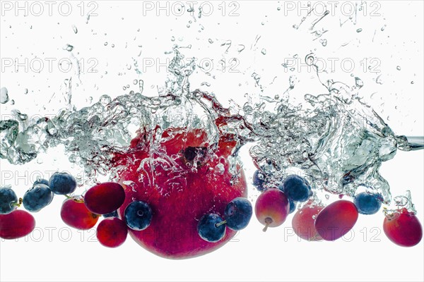 Studio shot of fruits falling into water