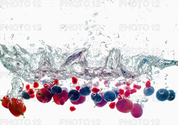 Studio shot of fruits falling into water