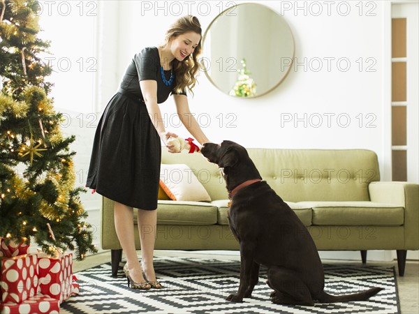 Young woman giving to dog Christmas present