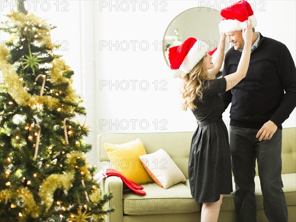 Young woman and man wearing Santa hats