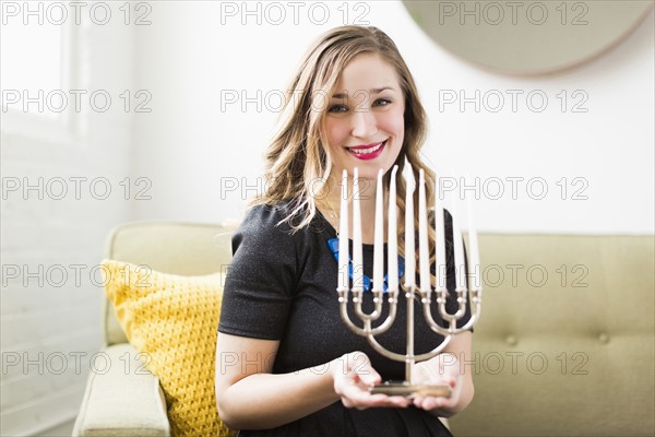 Portrait of young woman holding menorah