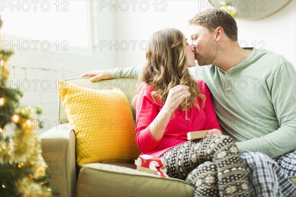 Young couple kissing on sofa at Christmas