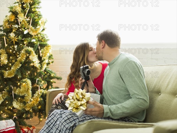 Young couple kissing on sofa at Christmas