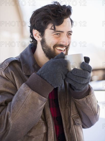 Portrait of man holding coffee mug outdoors in winter