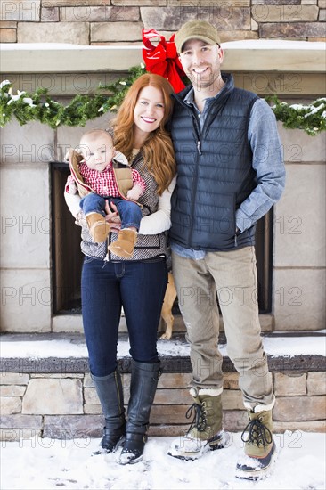 Portrait of family with one child (2-5 months) in front of house