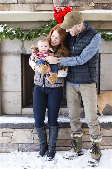 Portrait of family with one child (2-5 months) in front of house