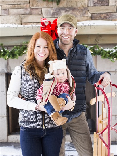 Portrait of family with one child (2-5 months) and sledge