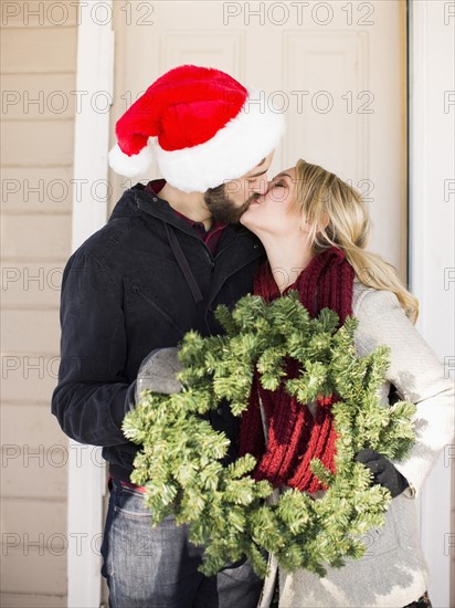 Young couple holding wreath and kissing